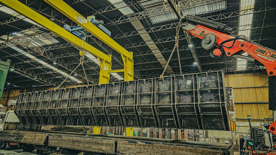 A robust industrial crane hoists a large metal container inside a spacious warehouse setting.