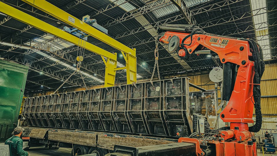 A large crane is used to load a container onto a truck inside a warehouse.